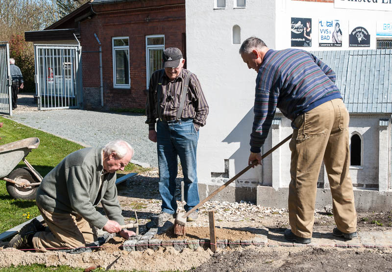 Jørgen Steffensen og Mogens Andersen knokler med brostene mens Eigil Bisgaard ser til at det udføres forskriftsmæssigt korrekt.